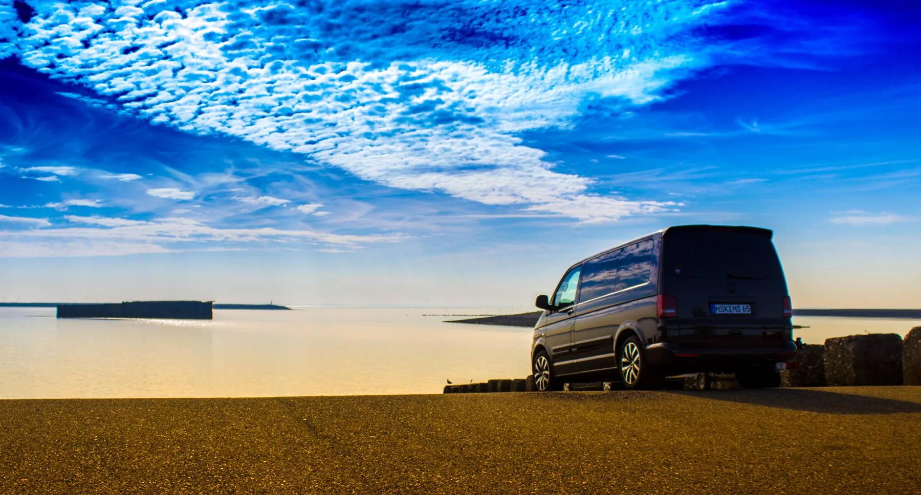 Camper am Meer bei tief stehender Sonne