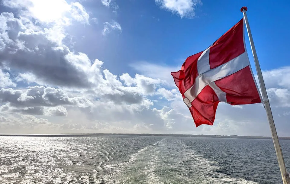 Dänische Flagge vor Himmel und Meer